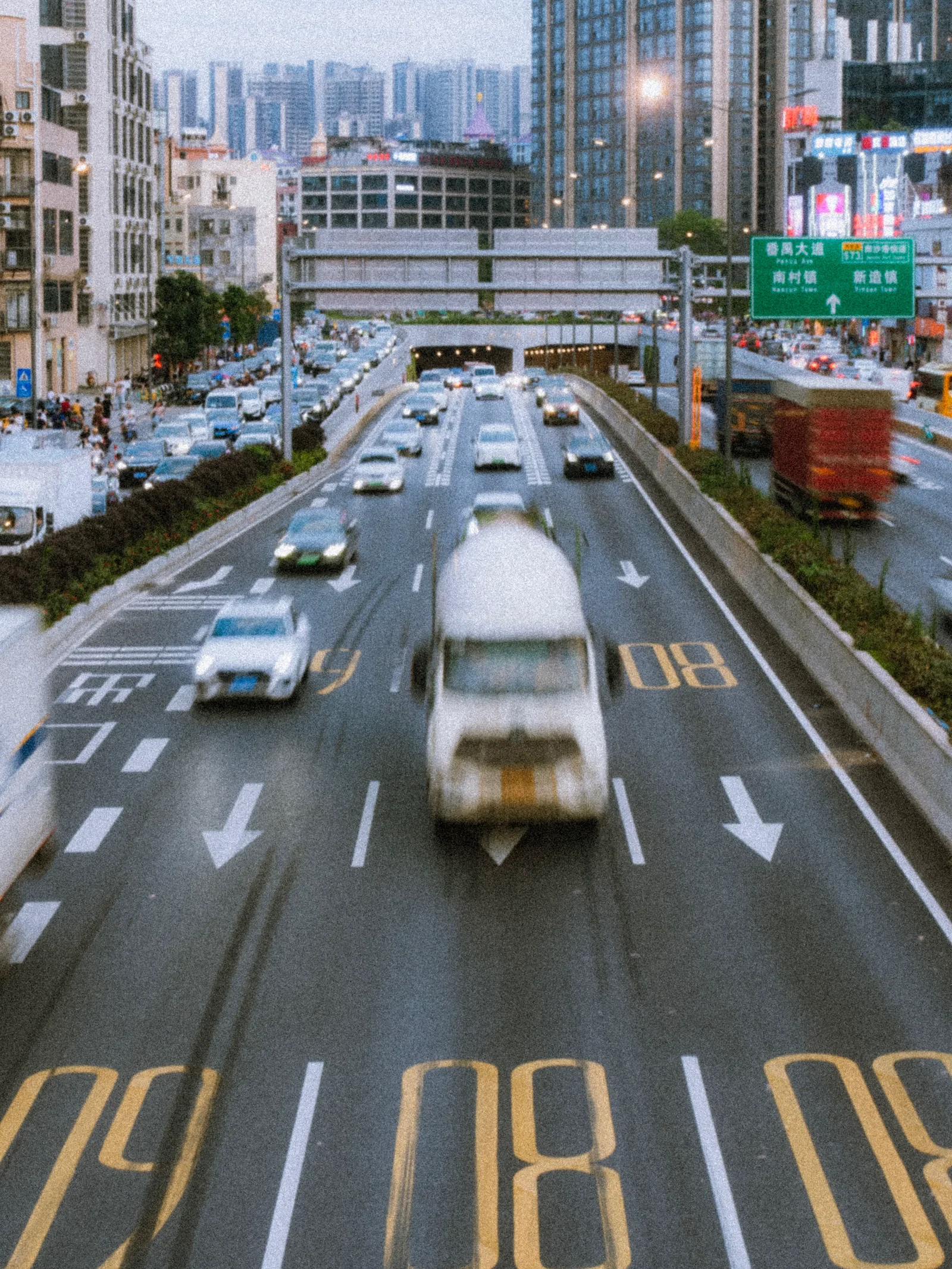 Motion-blurred cars and a tanker streaking through numbered highway lanes — life in the fastlanes, the literal kind.