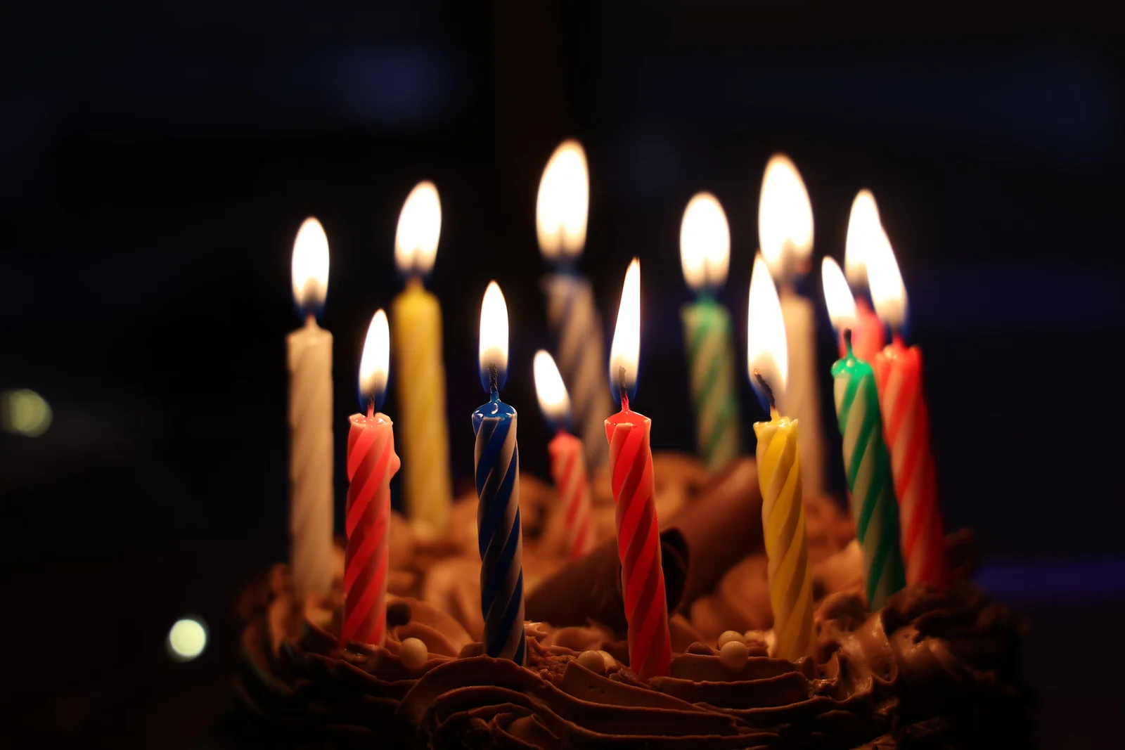 A chocolate birthday cake bristling with lit candles in the dark — Vortex blowing them out as it walks toward 1.0.
